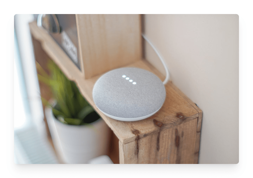round gray smart speaker on wooden shelf