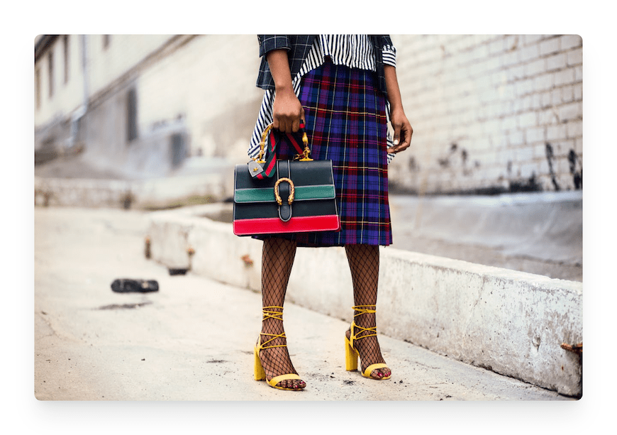 woman in plaid skirt holding multicolored leather handbag