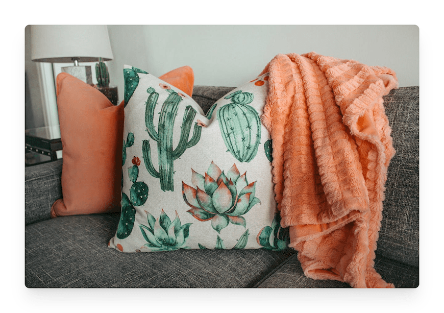 cactus pillow with orange throw on gray couch