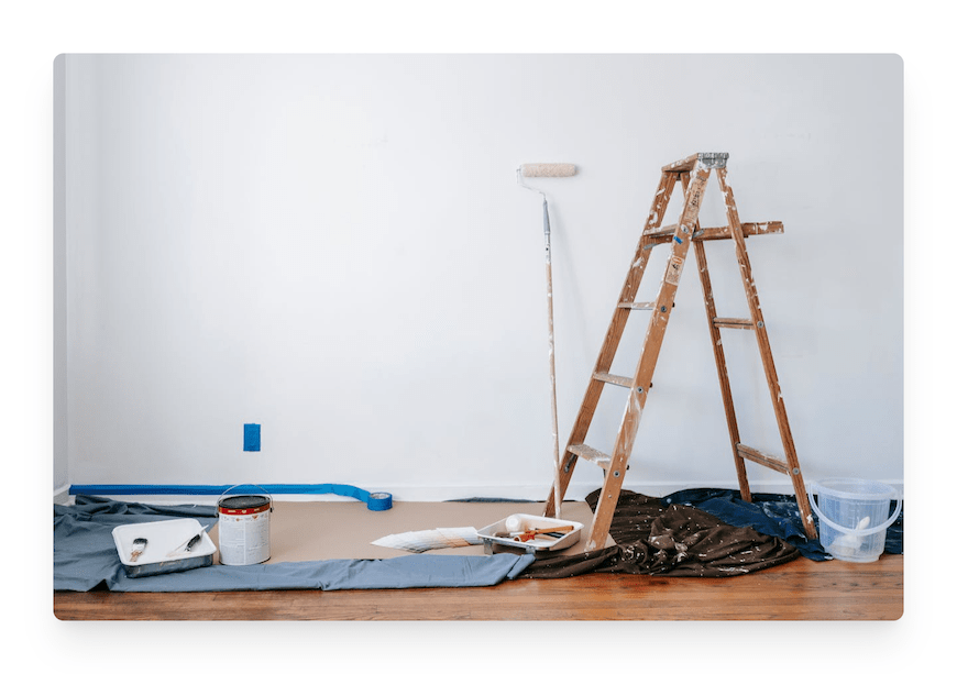 painting supplies and ladder next to wall